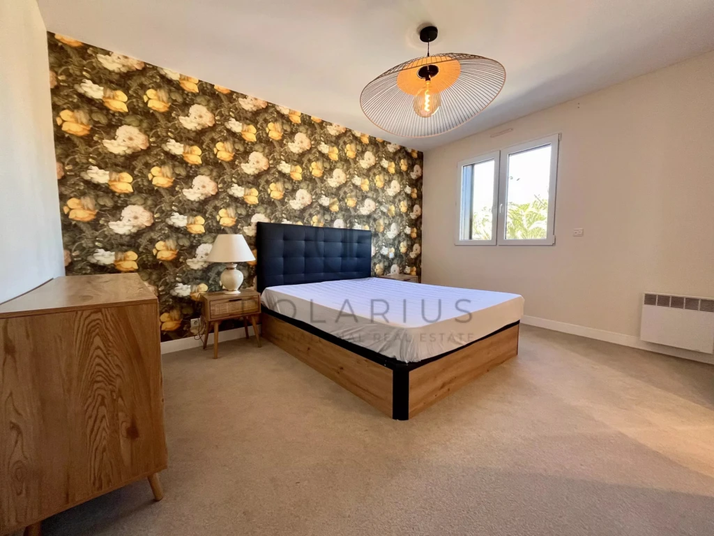 Chambre lumineuse avec un mur accent floral et un grand lit dans un appartement calme.
