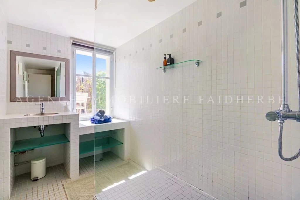 Salle de bain lumineuse avec espace pratique pour la vanité et douche séparée.
