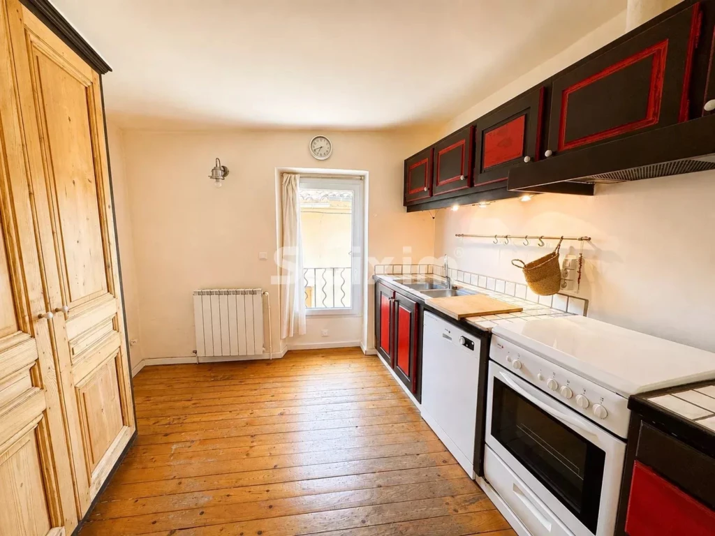 Cuisine lumineuse avec rangements modernes et accès à un balcon.