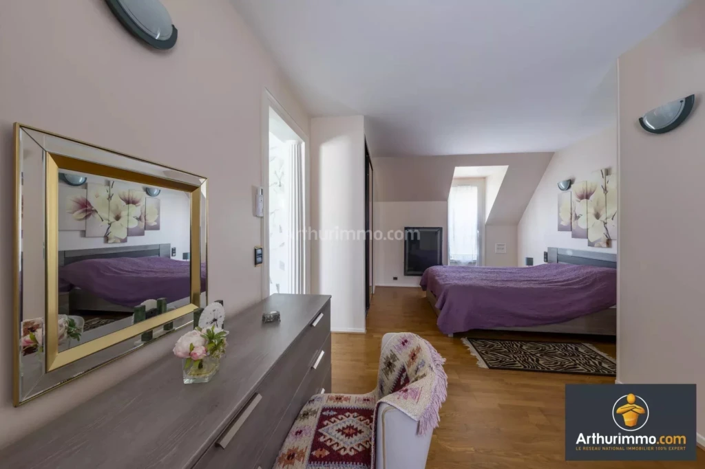 chambre moderne avec un grand lit, des murs clairs, un meuble avec un miroir, et des décorations florales.