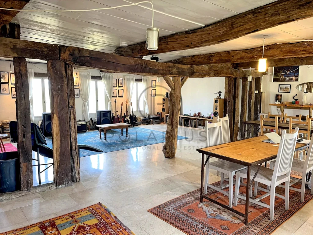 Spacieuse pièce de style rustique avec poutres en bois apparentes et mobilier élégant.