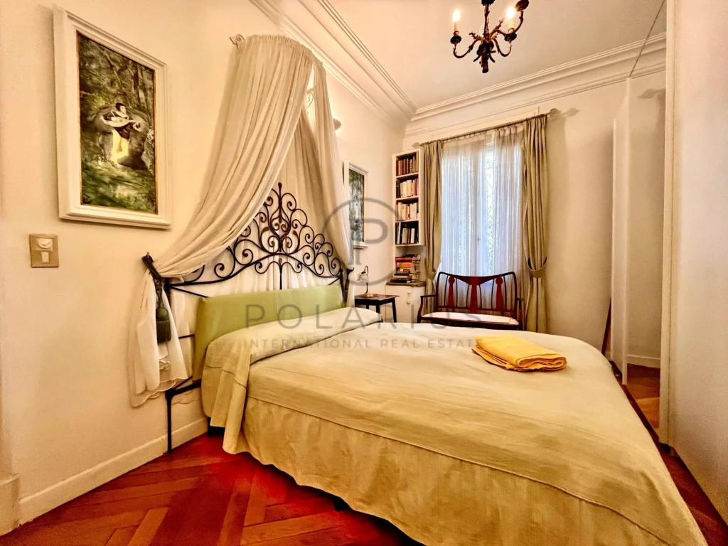 Chambre élégante avec un lit confortable, meubles classiques et lumière naturelle abondante.
