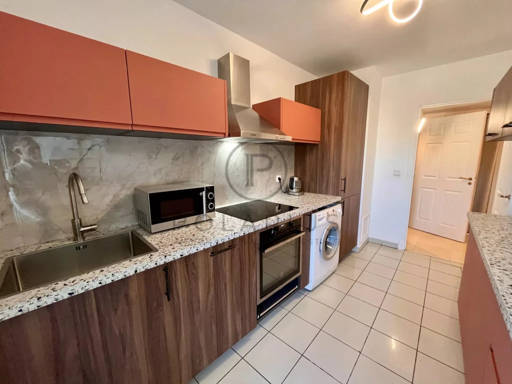 Cuisine moderne équipée avec plan de travail en granite et appareils électroménagers intégrés.