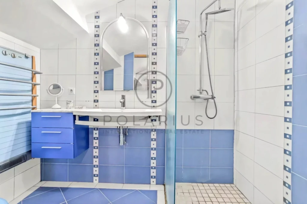 Salle de bains moderne avec carrelage bleu et blanc, un lavabo avec miroir, et une douche à l'italienne.
