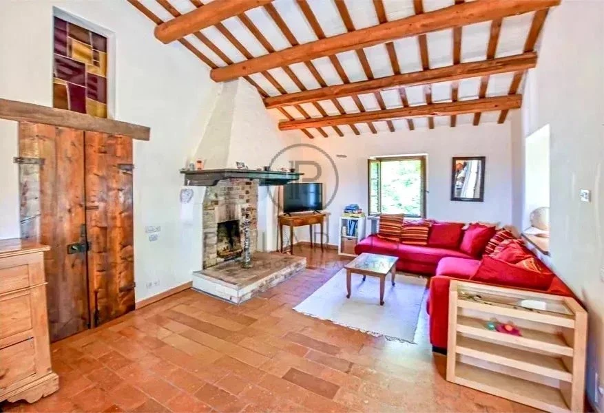 Salon chaleureux avec cheminée et poutres en bois apparentes, idéal pour la détente.