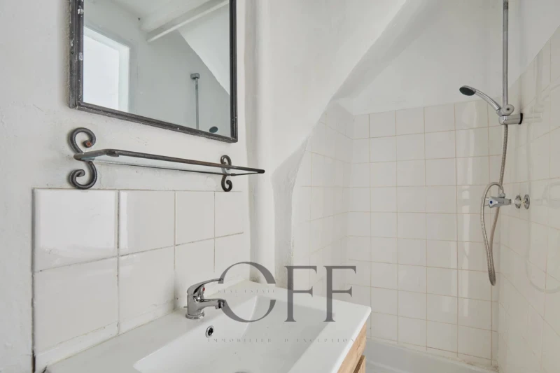 petite salle de bains avec un miroir un lavabo et une douche à carreaux blancs.