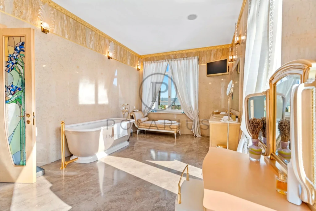 Une salle de bain luxueuse avec une baignoire, un grand miroir, un canapé, et des rideaux blancs.
