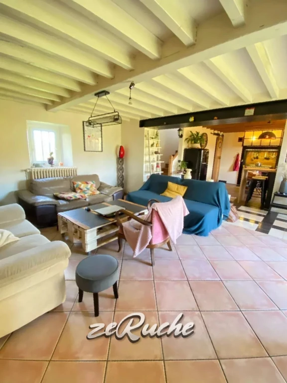 Un salon lumineux avec un plafond en poutres apparentes et un mobilier moderne.