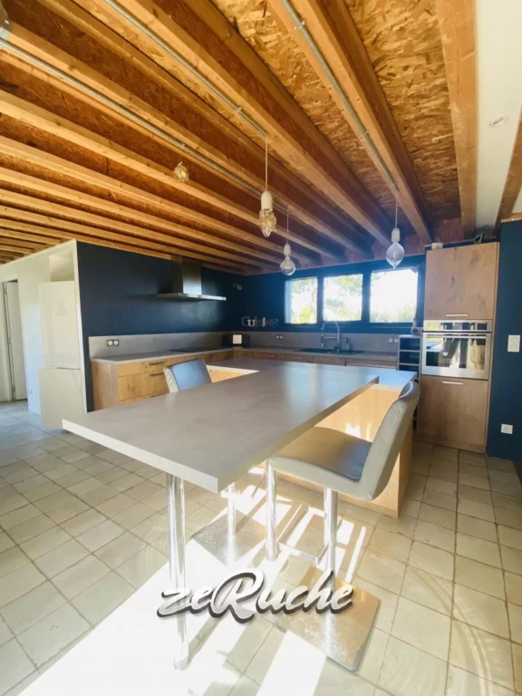 Cuisine moderne avec plafond en bois apparent et grands fenêtres lumineuses.