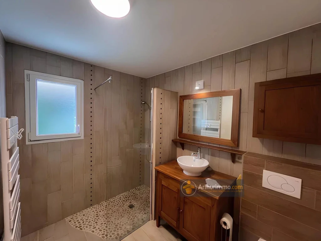 Salle de bain moderne avec douche à l'italienne et meuble en bois élégant.