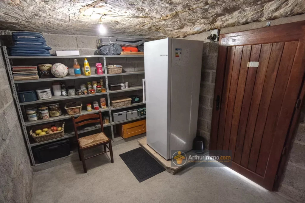 Cave aménagée avec des étagères, un réfrigérateur et un accès sécurisé.
