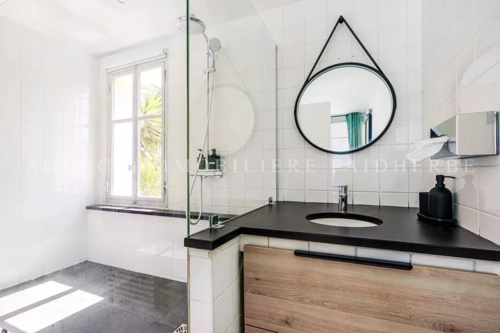 Belle salle de bain lumineuse avec une grande fenêtre et un miroir moderne.