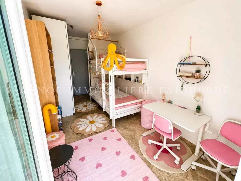 Chambre d'enfant lumineuse avec lits superposés et espace de travail dans un environnement charmant.
