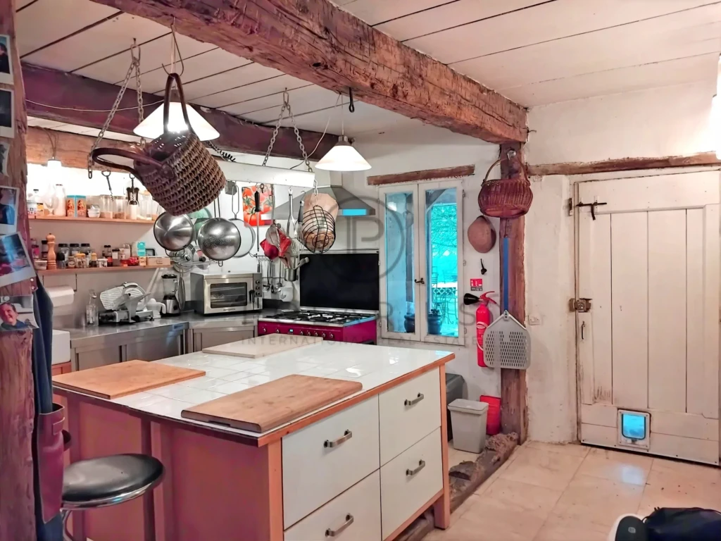 Cuisine chaleureuse avec poutres en bois apparentes et espace fonctionnel.