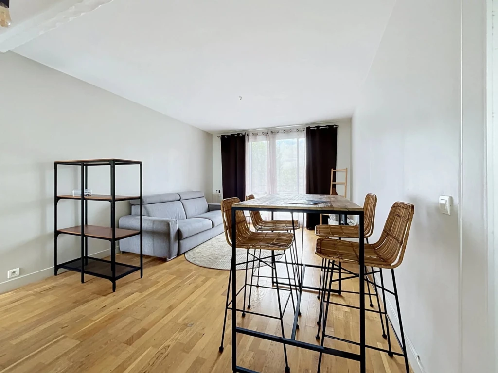 Salon lumineux avec canapé et espace repas contemporain.
