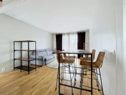 Salon lumineux avec canapé et espace repas contemporain.