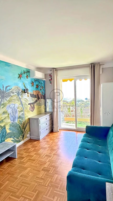 Salon lumineux avec un décor tropical et accès à un balcon.
