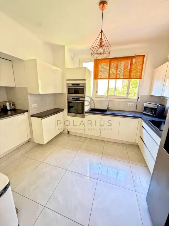 Cuisine lumineuse avec fenêtres et rangements modernes.