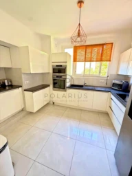 Cuisine lumineuse avec fenêtres et rangements modernes.
