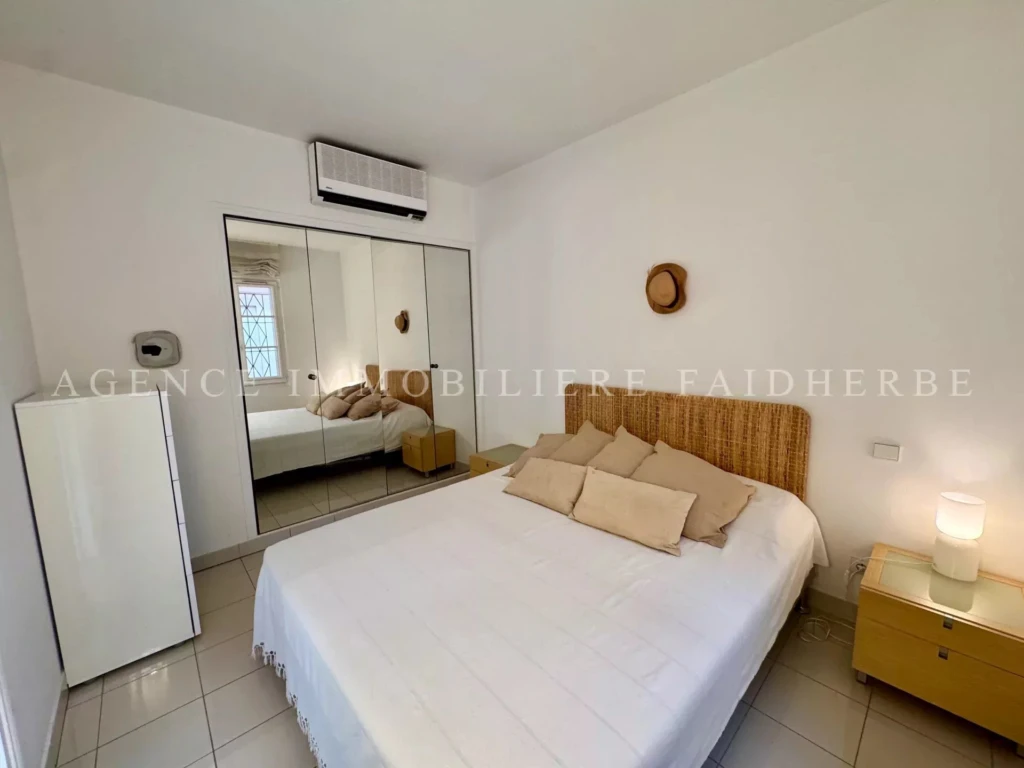 Chambre lumineuse avec un lit confortable et un mobilier moderne dans un appartement rénové.