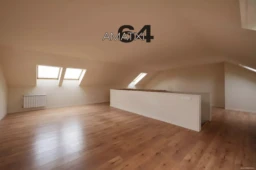 Empty attic with skylights on the eaves of the roof with floating chestnut wood flooring