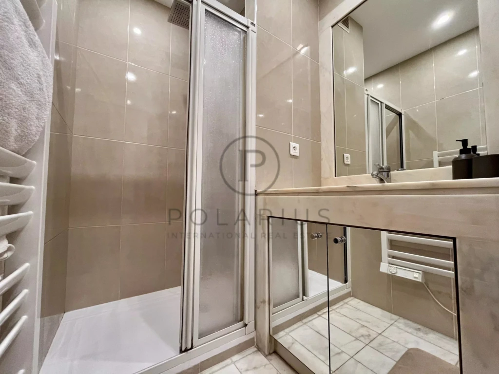 Salle de bain moderne avec cabine de douche et grand miroir.