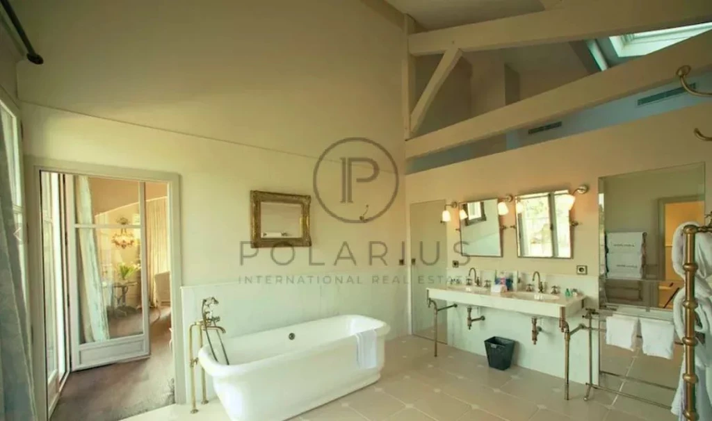 Une salle de bain lumineuse avec une baignoire à pattes, un grand miroir et un double lavabo.