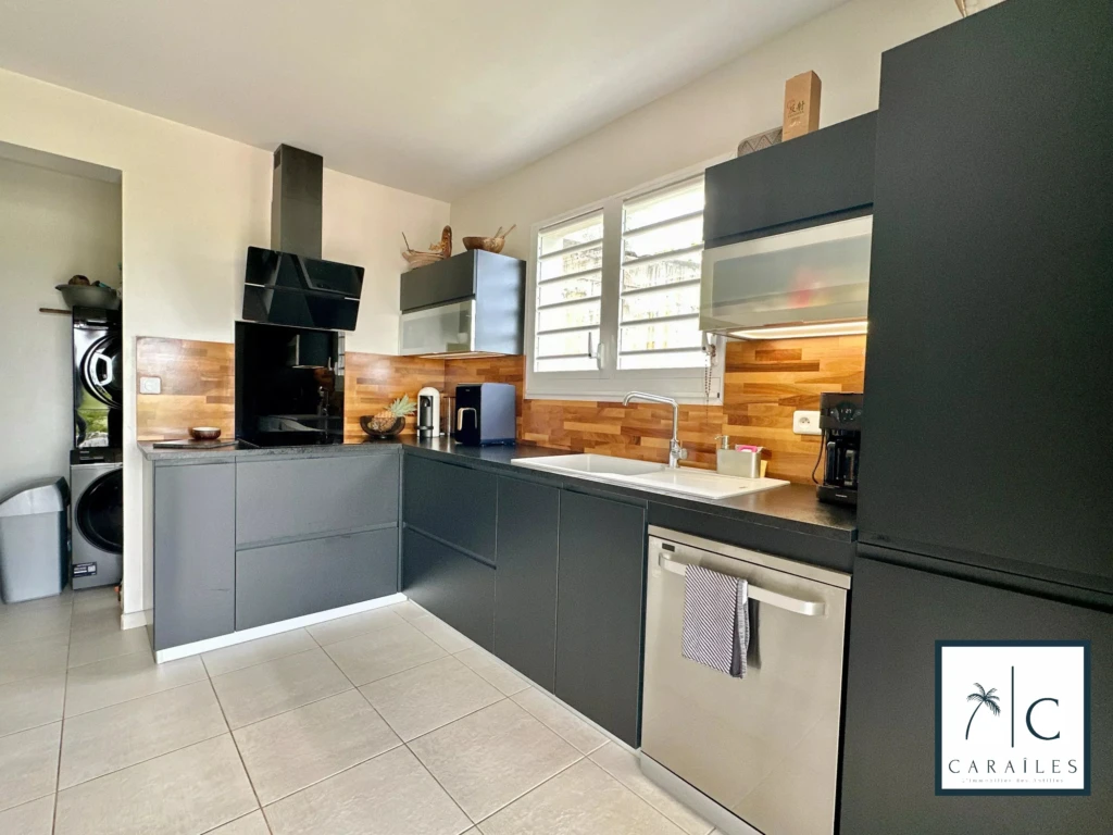 Cuisine moderne avec électroménagers intégrés et plancher en bois ou en carrelage.