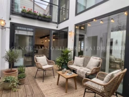 Balcon ensoleillé avec mobilier confortable et plantes luxuriantes, idéal pour se détendre.