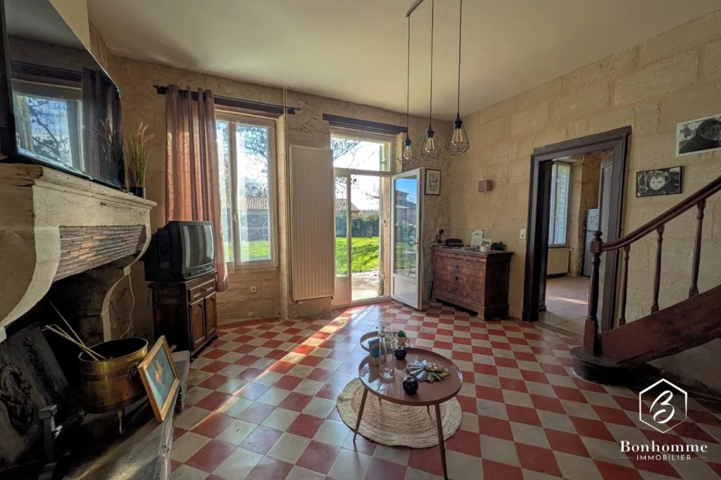 Salon lumineux avec cheminée et accès à un jardin verdoyant.