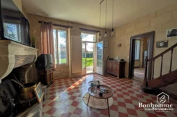 Salon lumineux avec cheminée et accès à un jardin verdoyant.