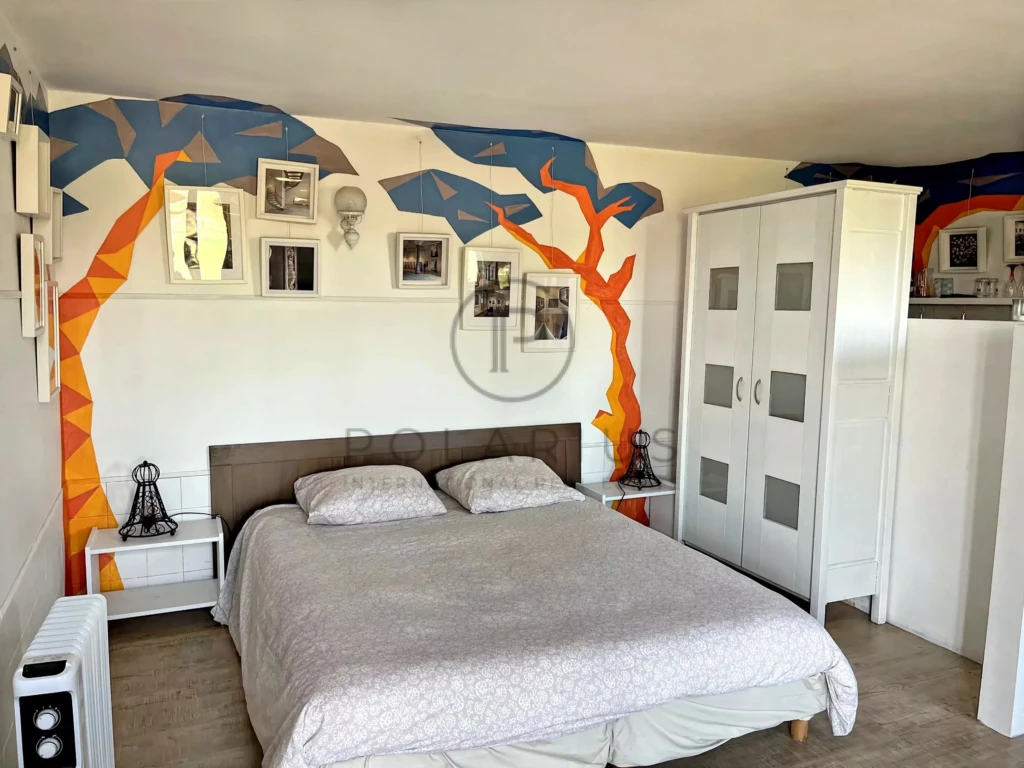 Chambre lumineuse avec mur décoratif arboré et mobilier moderne.