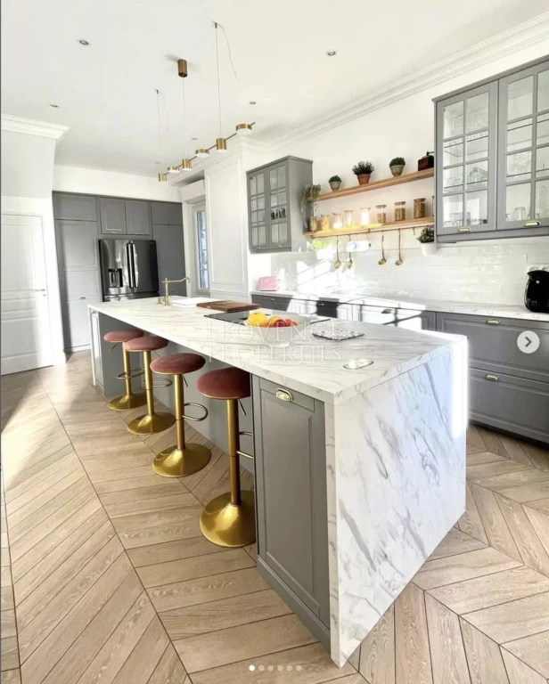 Une cuisine dînatoire résolument moderne et conviviale, sublimée par un grand îlot central en marbre et de nombreux rangements intégrés.