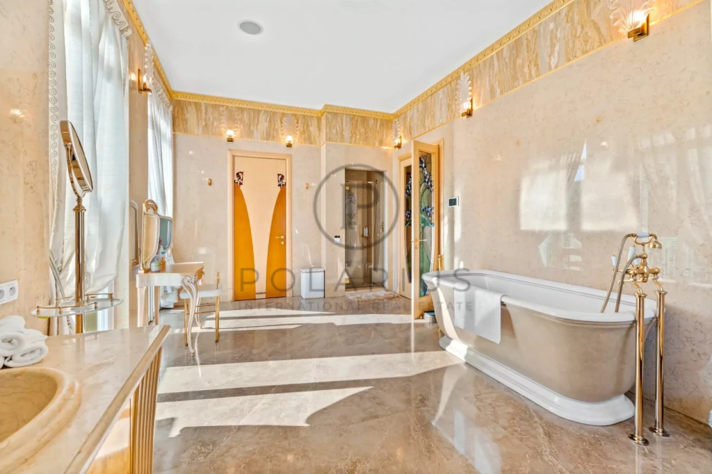 Salle de bain luxueuse avec baignoire élégante, miroir et double douche, éclairée par une lumière naturelle abondante.