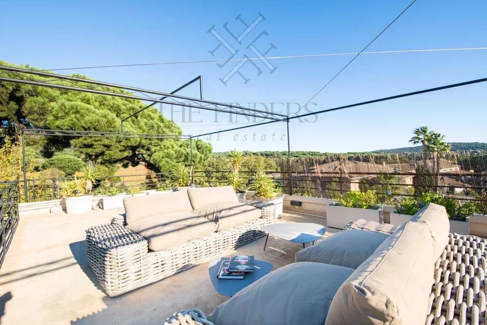 Terrasse ensoleillée avec canapés confortables et vue sur la nature.