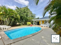 Belle maison avec piscine entourée de verdure tropicale.