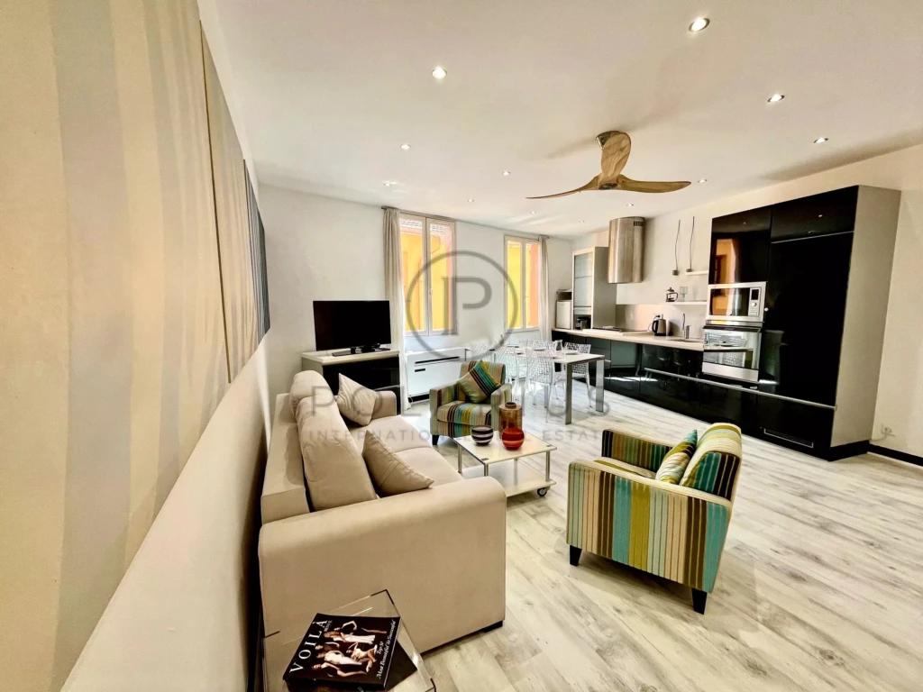 Salon lumineux et moderne avec canapé confortable et cuisine équipée ouverte.