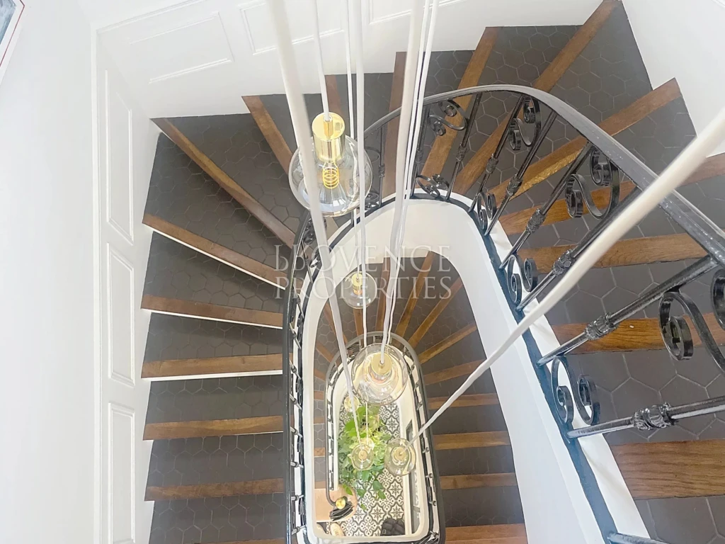 Vue plongeante sur la courbe parfaite de l'escalier, illuminé par une suspension moderne cascade de lumières.