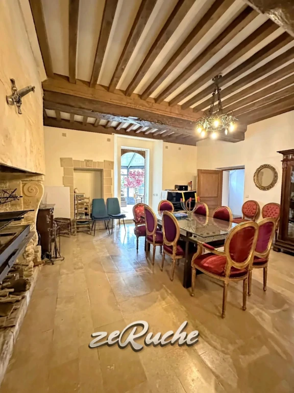 Belle salle à manger spacieuse avec poutres en bois et cheminée classique.