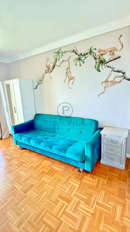 Salon lumineux avec un mur décoré d'une fresque végétale unique.