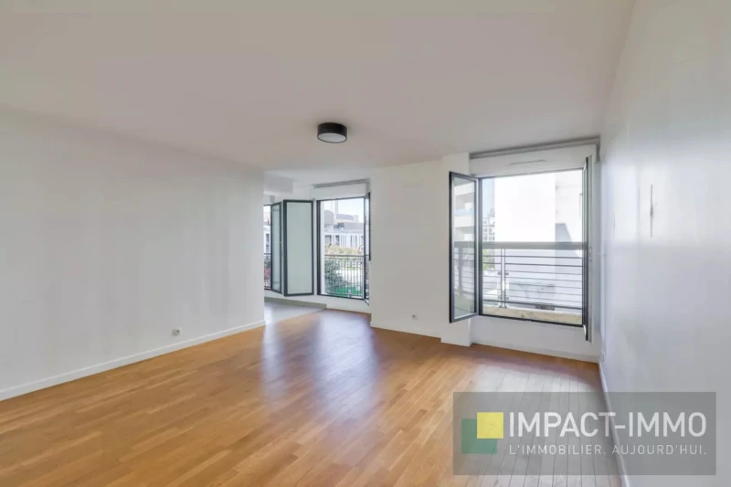 Un séjour lumineux avec un sol en parquet et des fenêtres en doubles vitrages ouvertes sur un balcon.