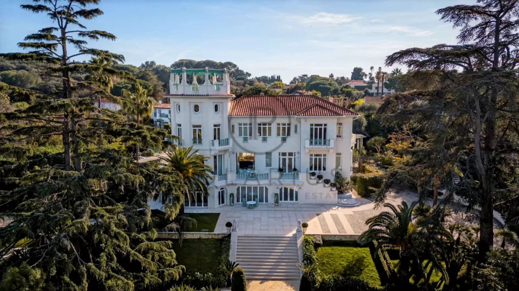Grande villa blanche entourée d'arbres avec un jardin élégant.