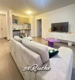 Salon lumineux avec un mobilier moderne et une télévision à écran plat.