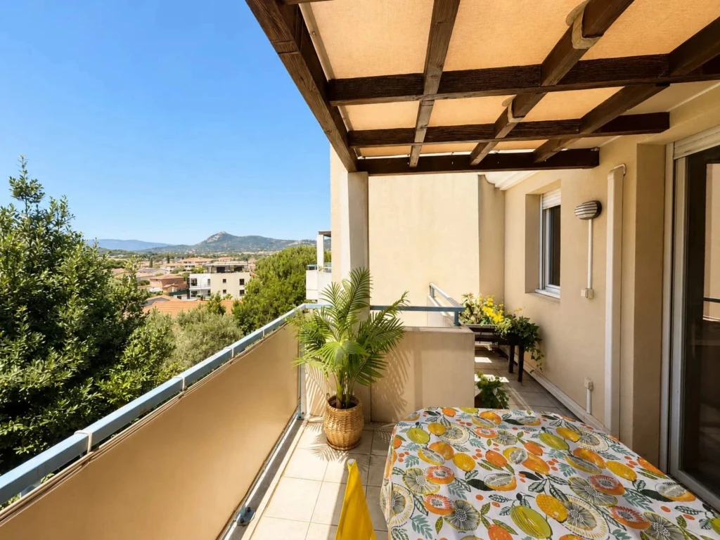 Espace terrasse avec pergola en bois, aménagé d'un coin repas offrant une vue panoramique sur les collines.