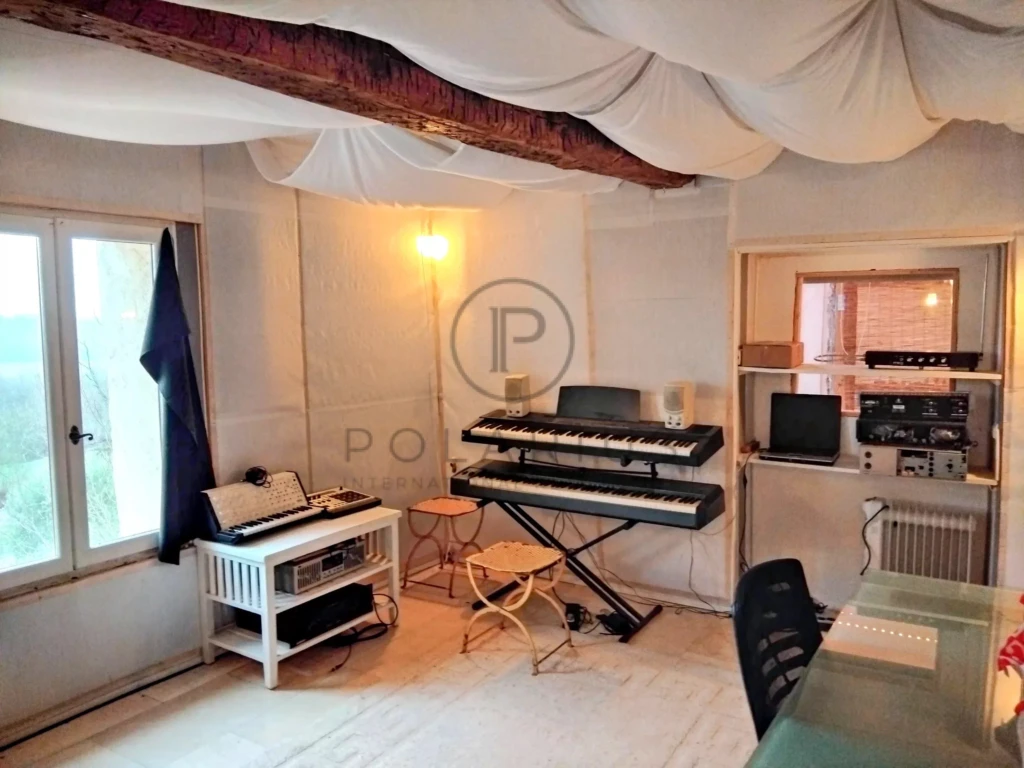 Une salle de musique lumineuse avec un piano, un clavier et un équipement audio.