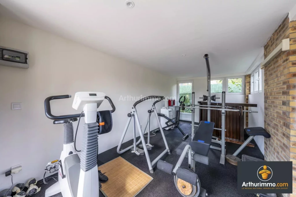 MOULIGNON Salle de sport à domicile avec divers équipements d'exercice, comme un vélo elliptique et un banc de musculation.