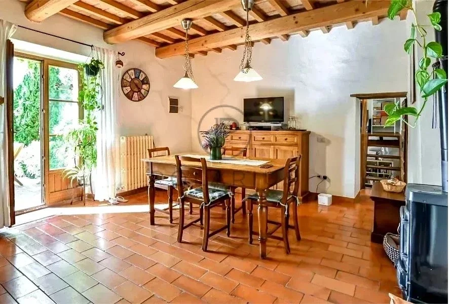 Salon lumineux avec cheminée, parquet en terre cuite et accès à un jardin.