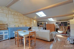 Charmant loft lumineux avec coin repas en bois et bibliothèque intégrée.