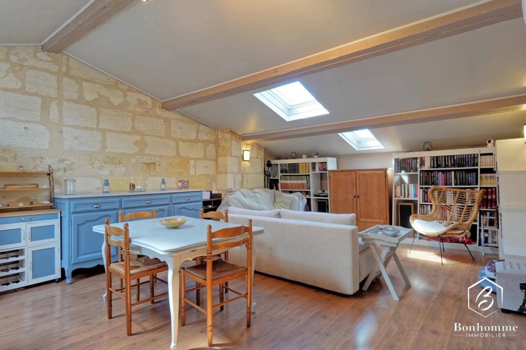 Charmant loft lumineux avec coin repas en bois et bibliothèque intégrée.