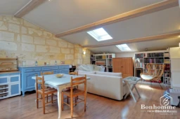Charmant loft lumineux avec coin repas en bois et bibliothèque intégrée.